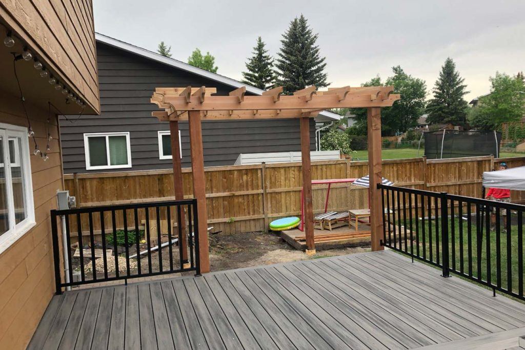 photo of a backyard with a wood pergola and deck