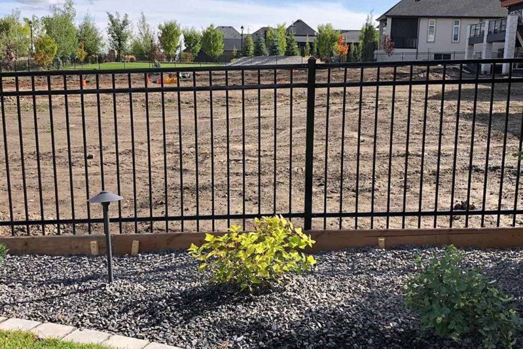 a black iron fence with unfinished lanscaping