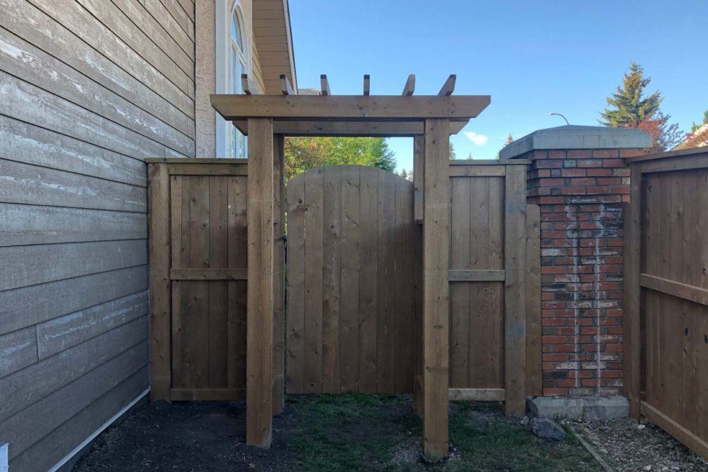 a backyard wooden gate with brick pillars