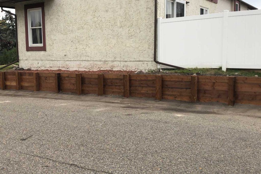 a wooden retainer wall at the side of a house