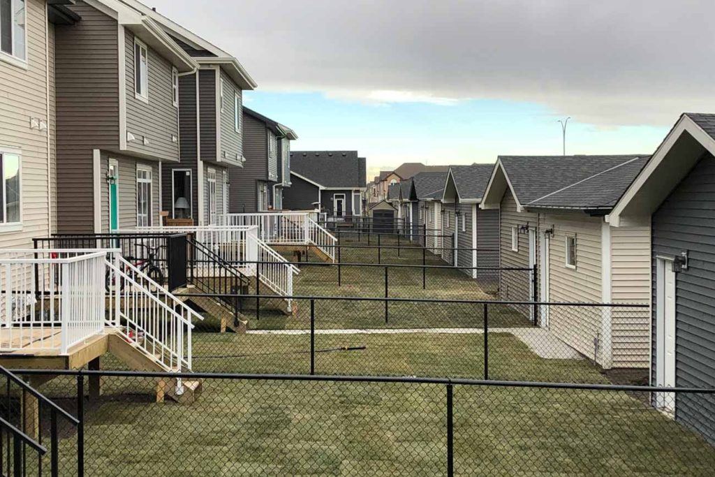 multiple black chain link fences separate neighbouring backyards